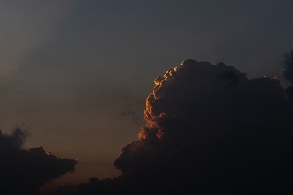 a plane flying through a cloudy sky at sunset