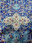 Intricate and colorful ceramic tiles featuring elaborate floral and geometric patterns. The design includes vibrant blue, orange, green, and white colors with detailed, interwoven motifs and decorative blossoms.