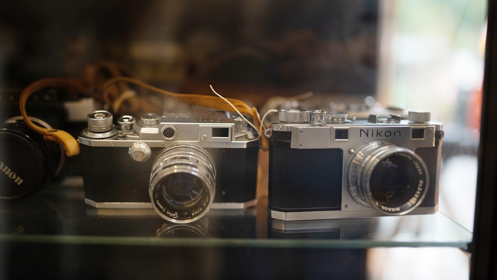 a couple of cameras sitting on top of a glass shelf