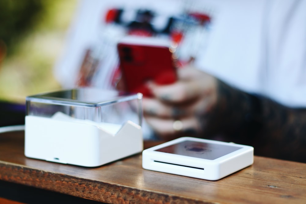 une personne assise à une table avec un téléphone cellulaire