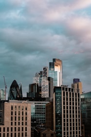 A city skyline partially covered by a futuristic dome with dark clouds outside.