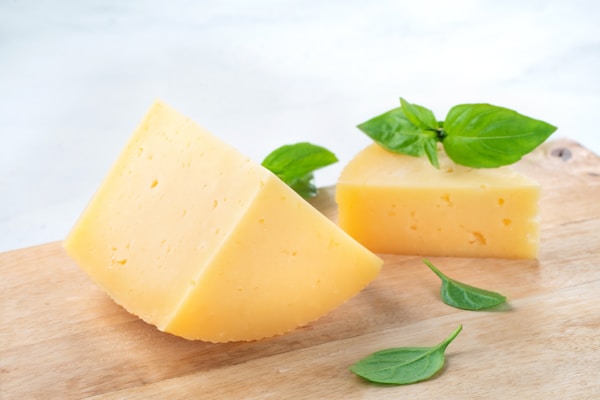 A piece of cheese with a leaf on top of it
