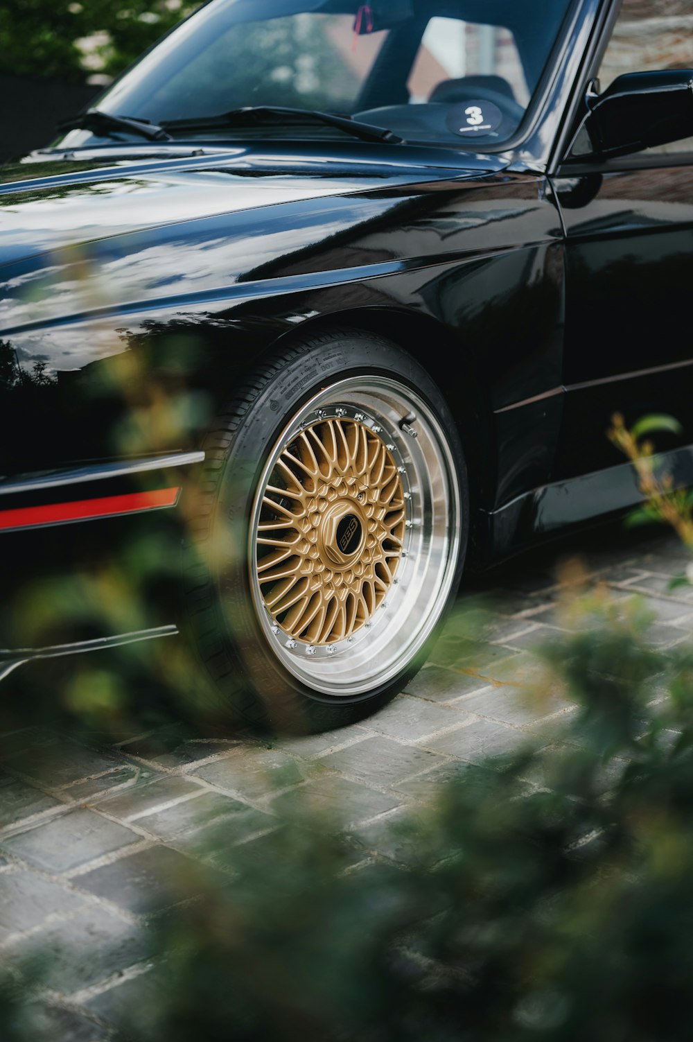 a black car with gold rims parked in front of a building