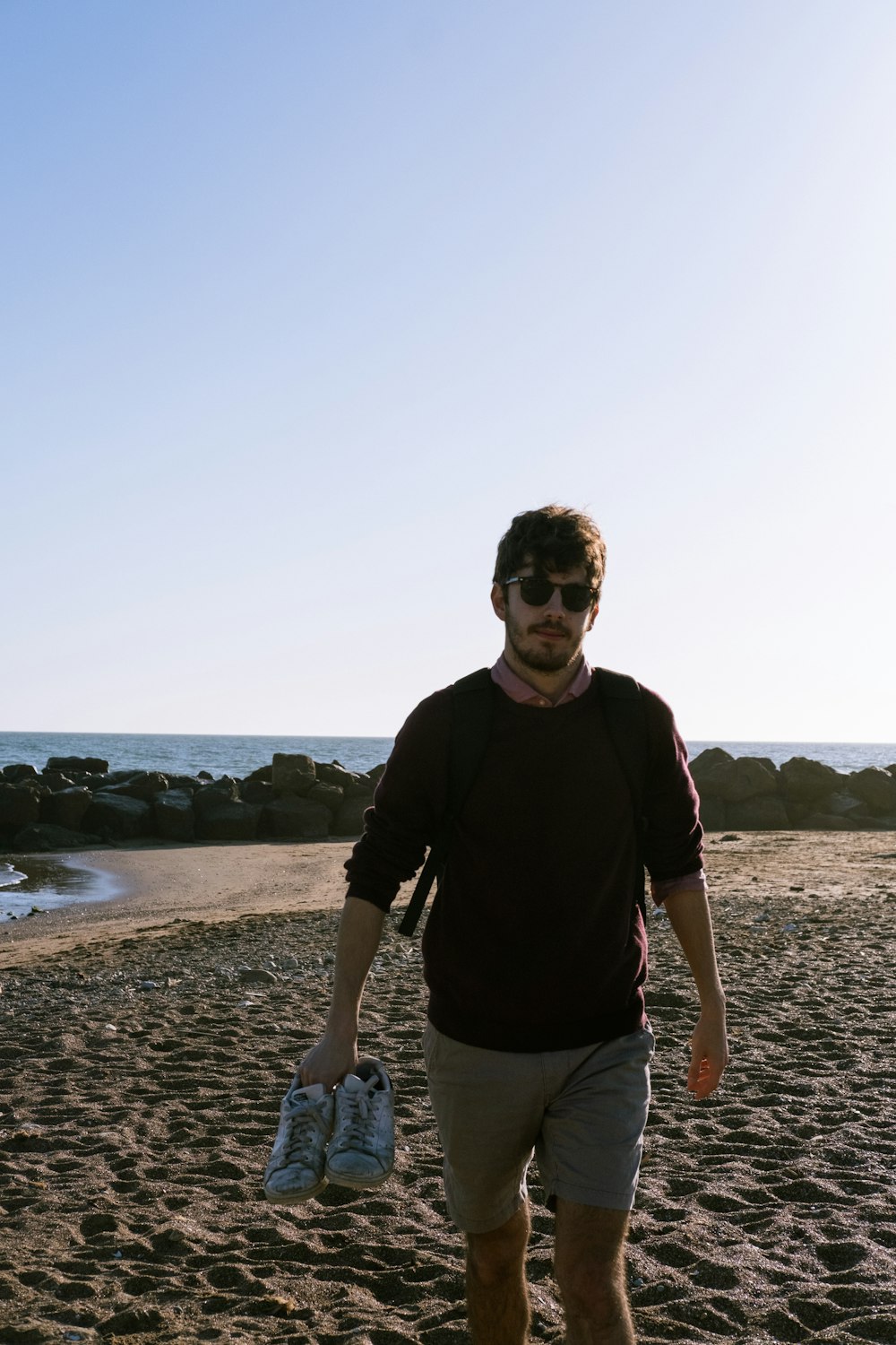 Un hombre caminando por una playa de arena junto al océano