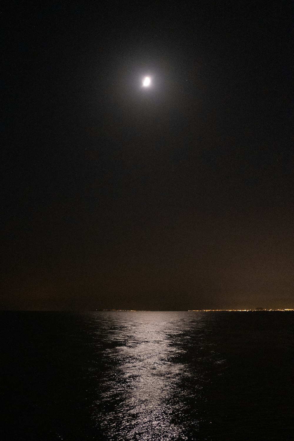 a full moon is seen over the ocean at night