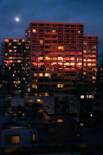 Nighttime cityscape with illuminated apartment windows reflecting warmth and luxury.