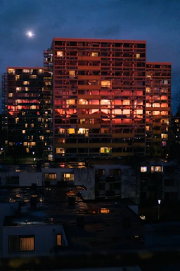 Nighttime cityscape with illuminated apartment windows reflecting warmth and luxury.
