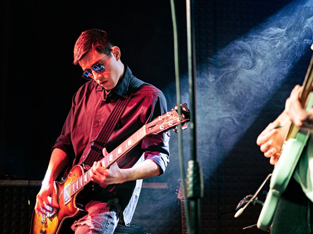 a man playing a guitar in front of a microphone