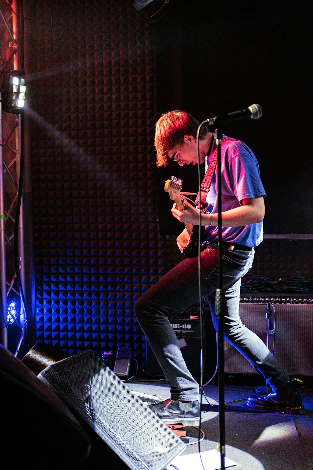 a man standing on a stage playing a guitar