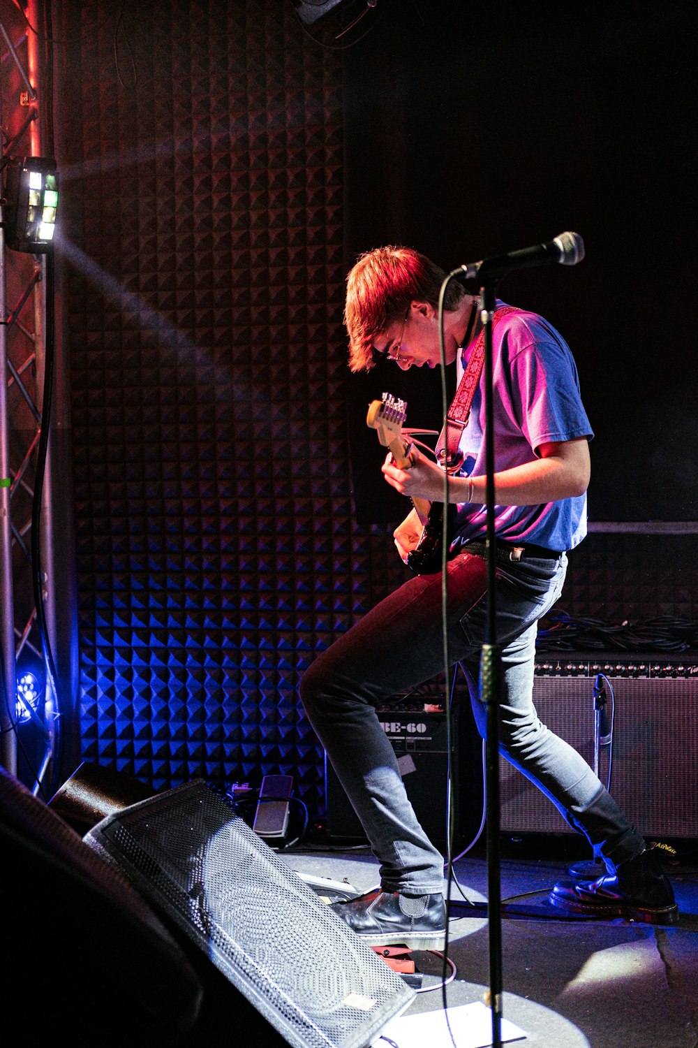 um homem em pé em um palco tocando um violão