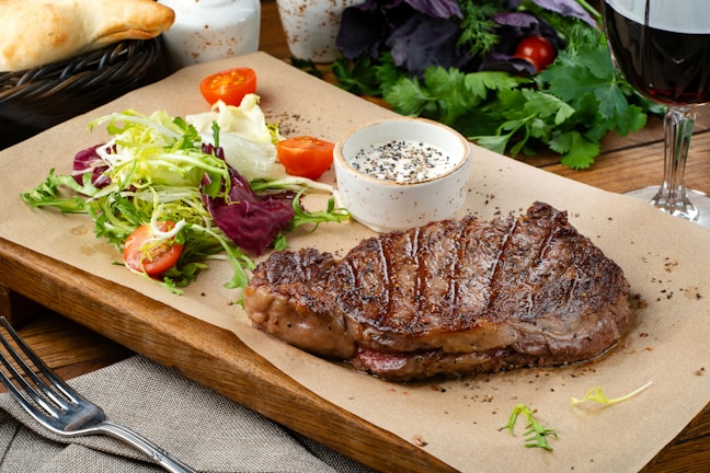 a steak with a side of salad and a glass of wine