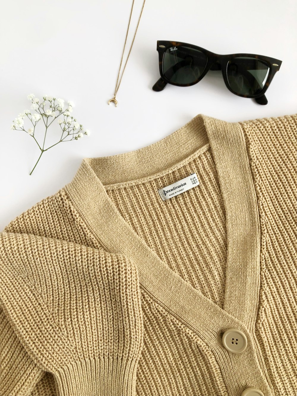 a pair of sunglasses and a sweater on a white surface