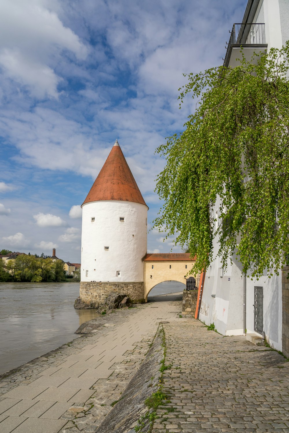 a white tower with a red roof next to a body of water