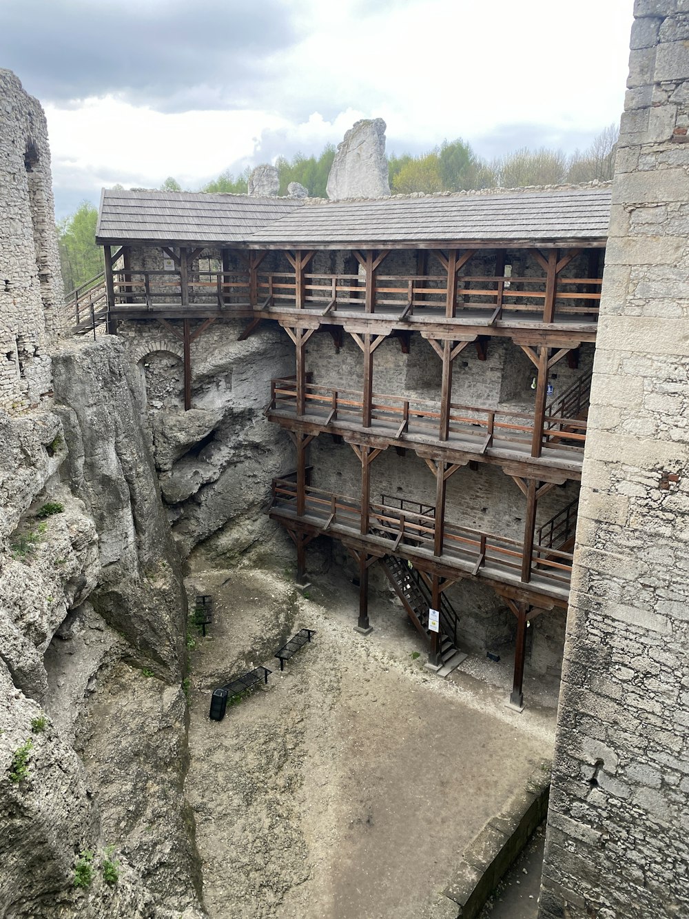 a stone building with a wooden balcony next to a cliff