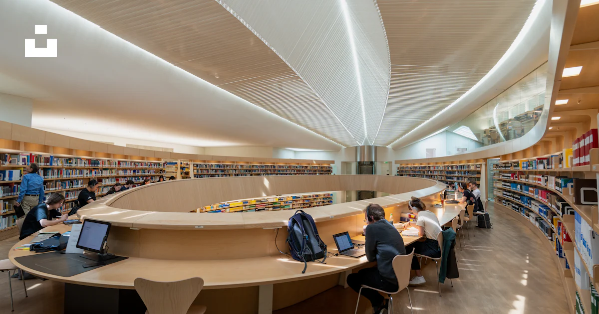 A library filled with lots of books and people sitting at tables photo ...