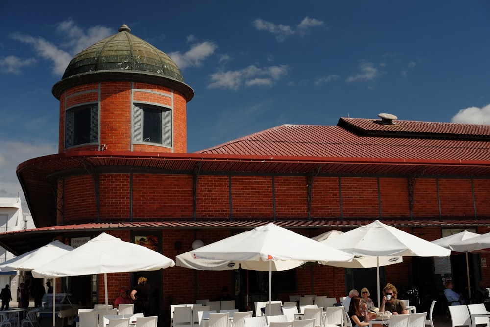 a red brick building with white tables and umbrellas