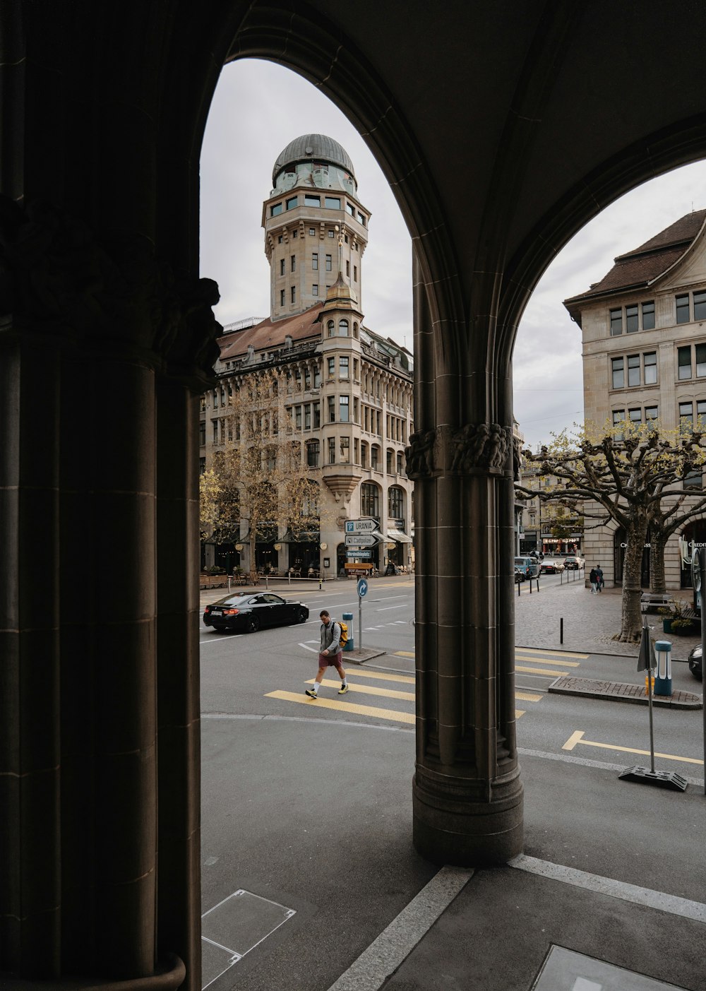 a person walking down a street in front of a tall building