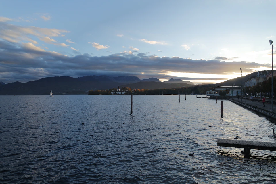 Serene lake scene with boat and pier at sunset, surrounded by orange and blue sky