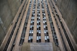 A towering building with numerous windows and air conditioning units. The structure is made of concrete and appears to be part of an urban setting. The words 'Criminal Courts Building' are visible at the base of the building.