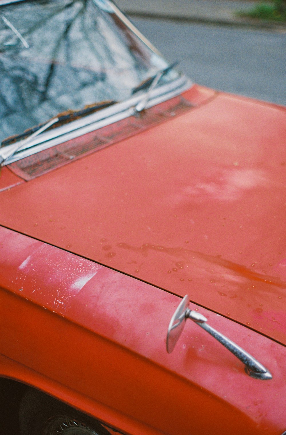 an old red car with a rusted hood