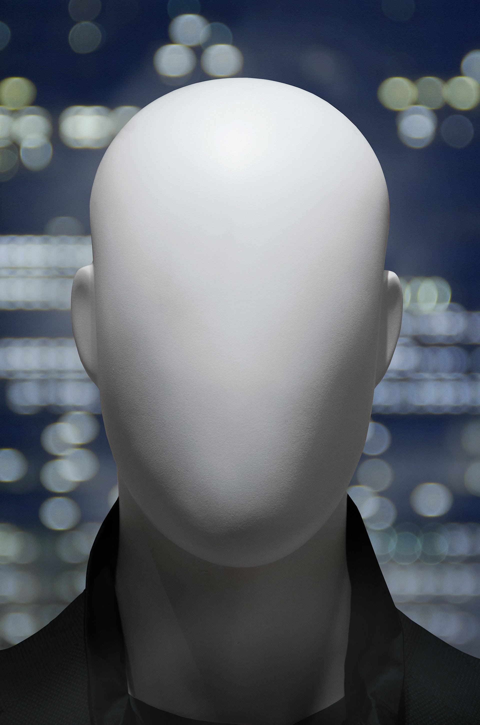 a white mannequin's head in front of a cityscape