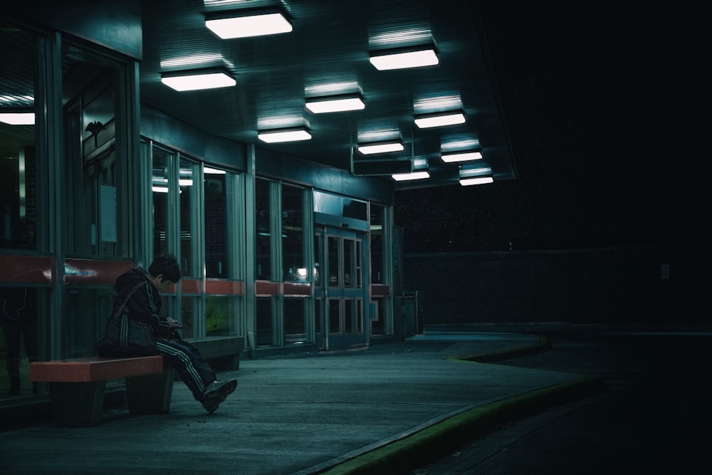 a person sitting on a bench at night
