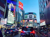 A busy city street with multiple cars featuring bright, eye-catching advertisements.