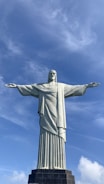a large statue of christ standing in front of a blue sky