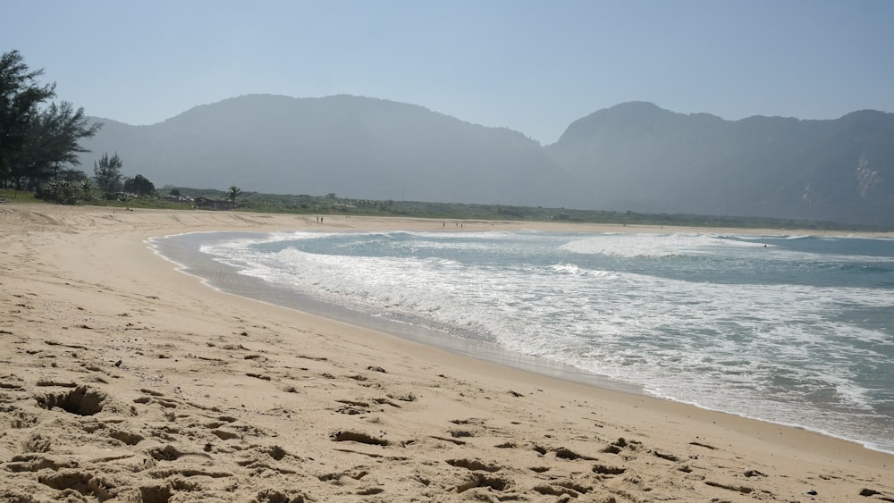 a sandy beach with mountains in the background