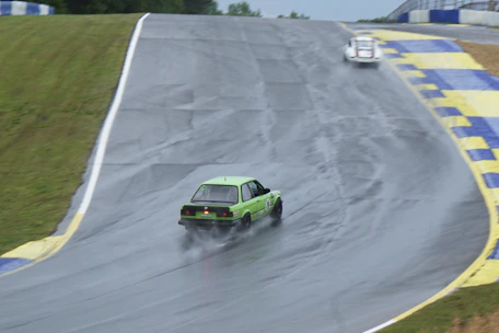 a green car driving down a race track