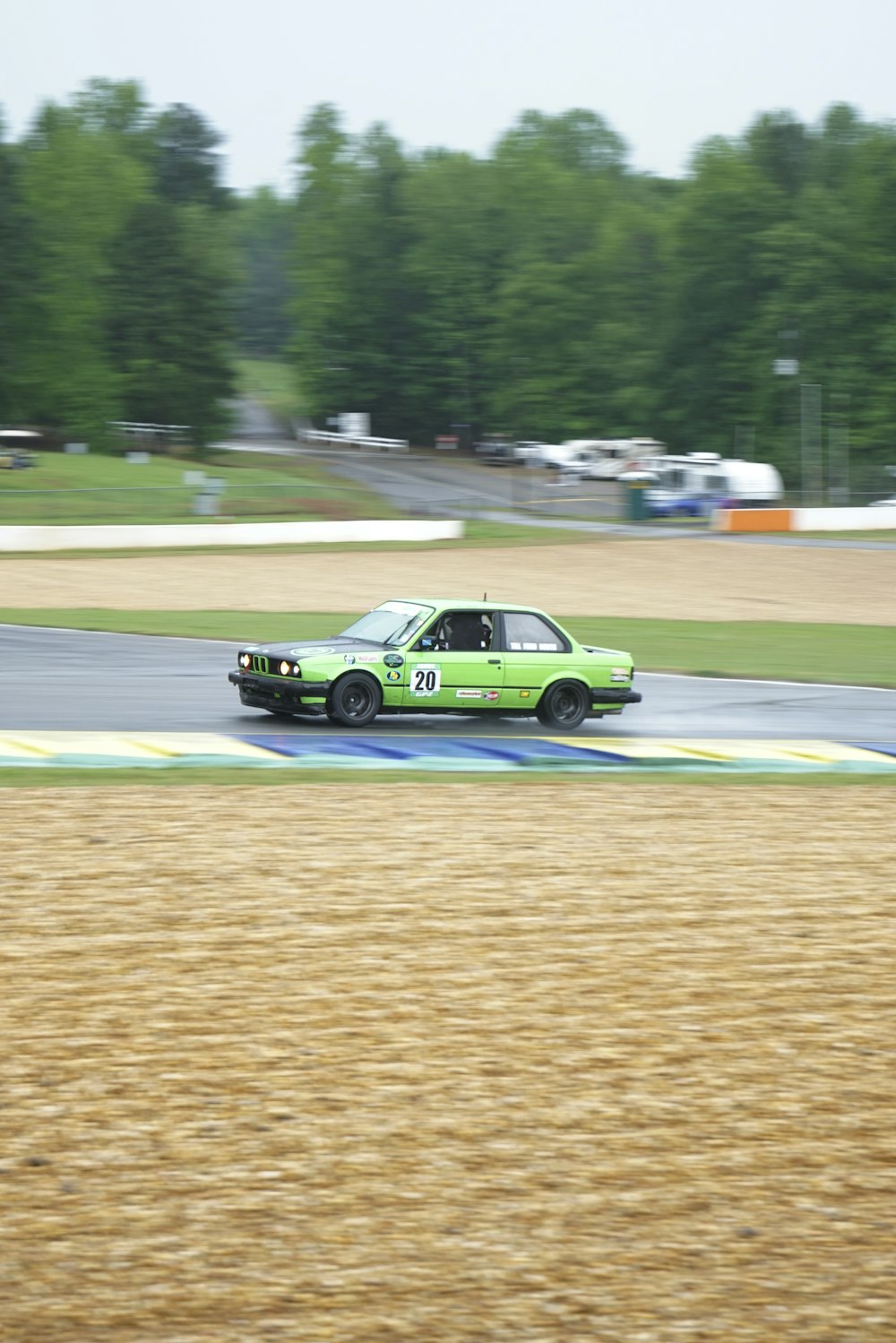 a green car driving down a race track