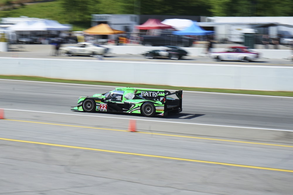 a green race car driving down a race track