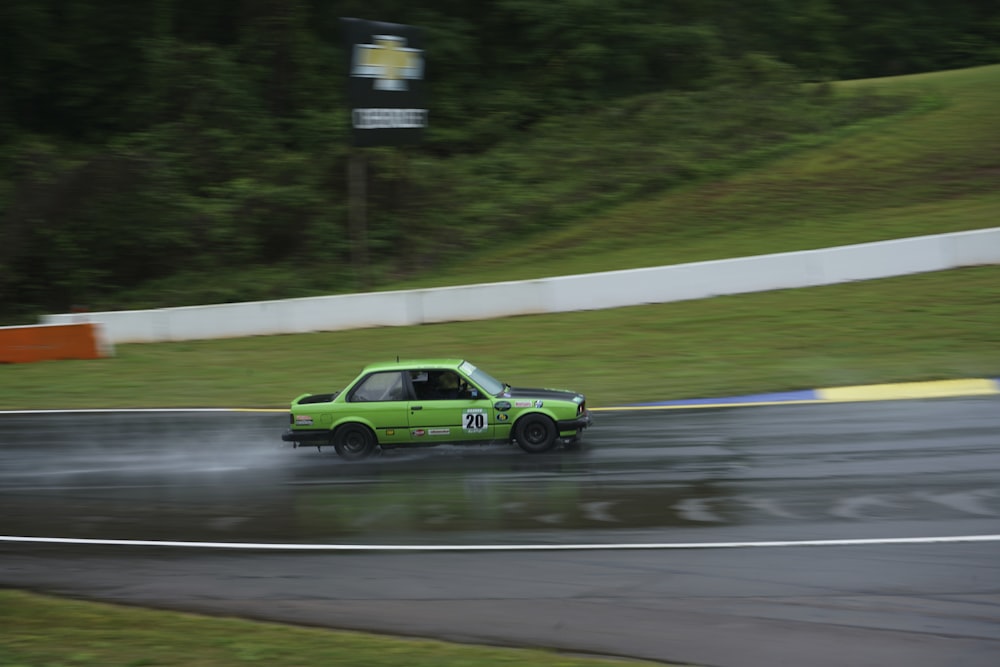a green car driving down a wet track