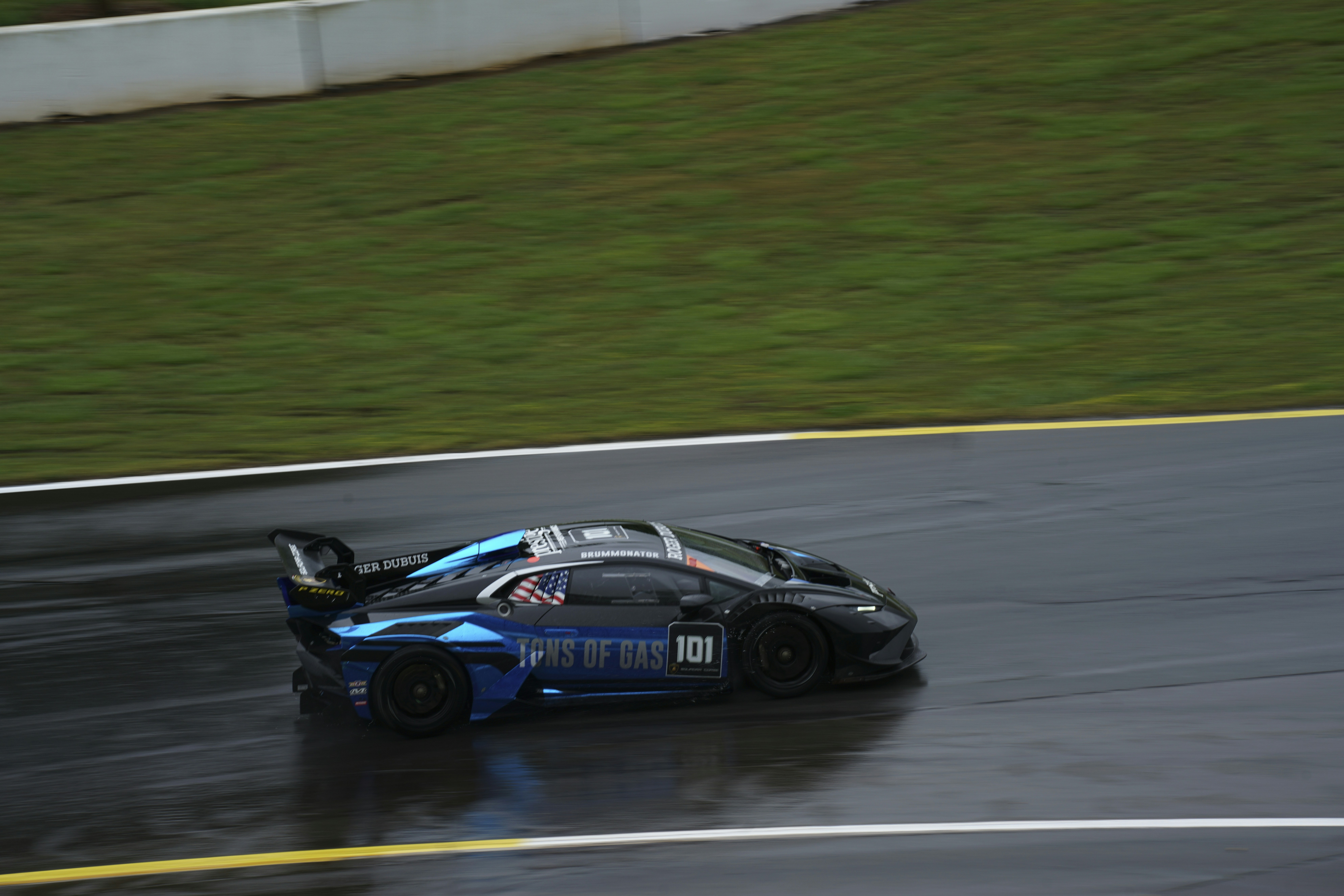 A blue race car driving down a wet track photo – Free Racing Image on ...