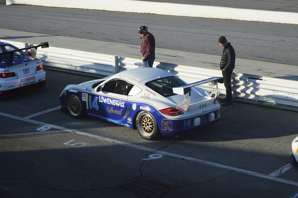 a man standing next to a car on a race track