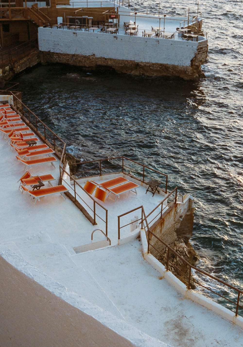 a group of orange lounge chairs sitting on top of a pier