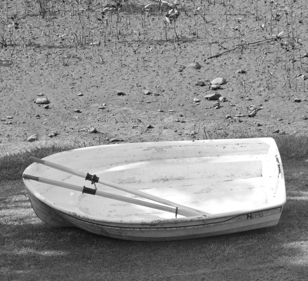 a white boat sitting on top of a dirt field