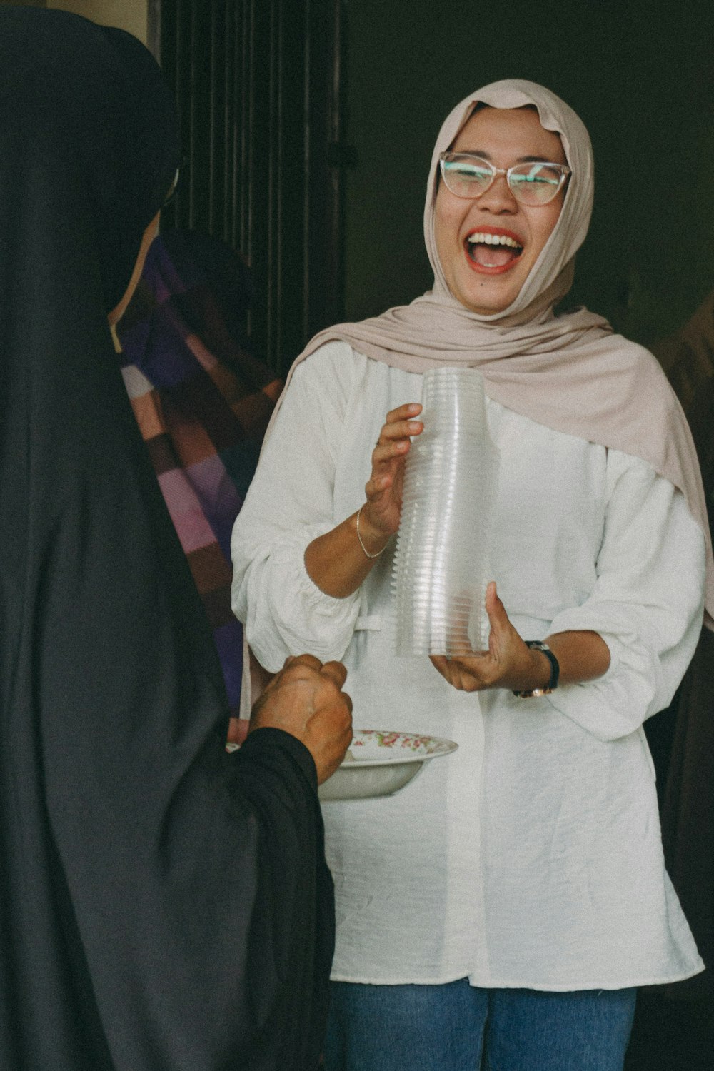 a woman in a hijab holding a plate of food