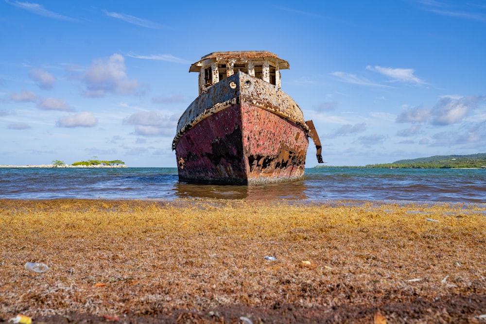 a rusted out boat sitting on top of a sandy beach