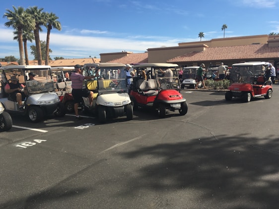 A friendly salesperson showing a variety of golf carts to a smiling customer on a sunny day.