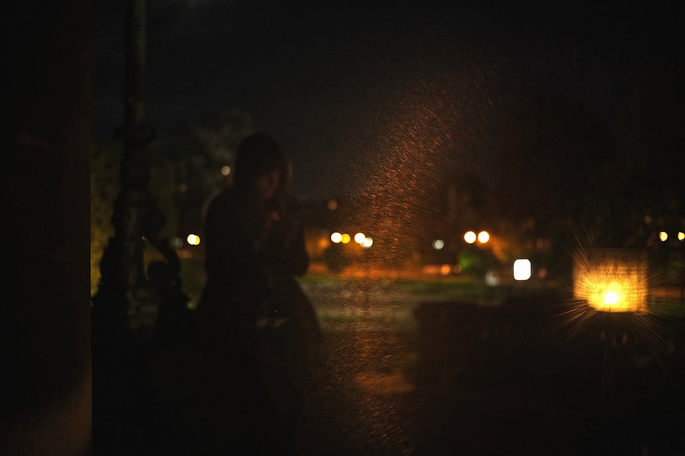 a woman standing next to a street light at night