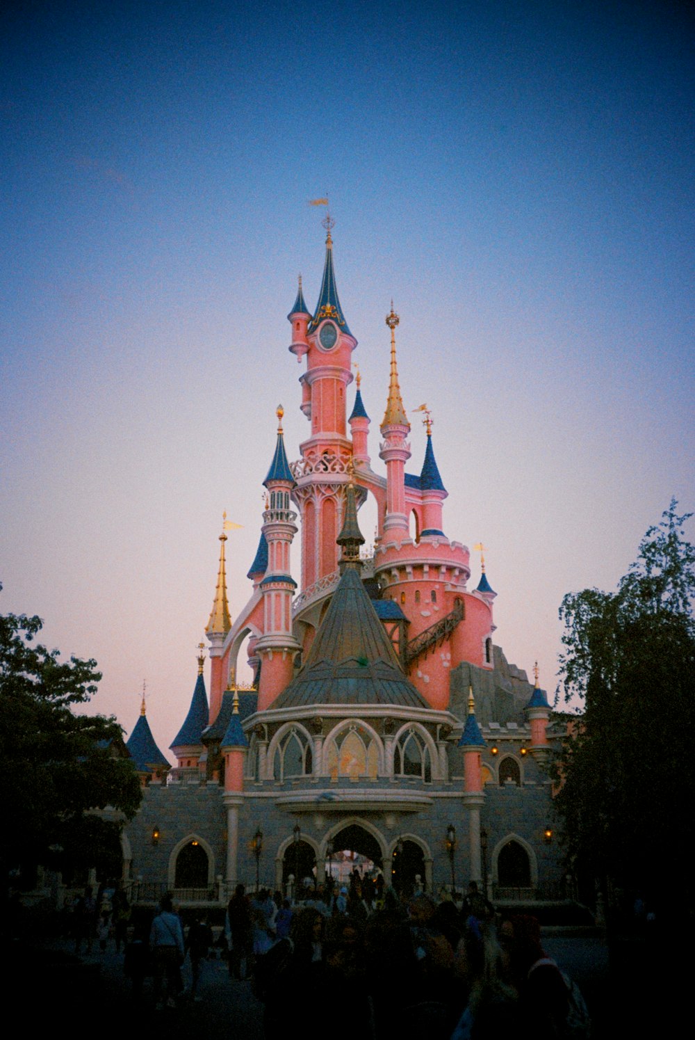 a pink and blue castle with lots of people around it