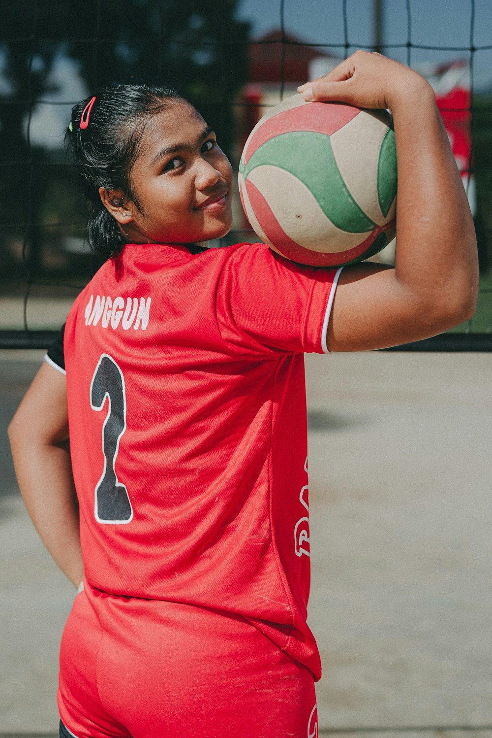 a woman in a red shirt holding a volleyball