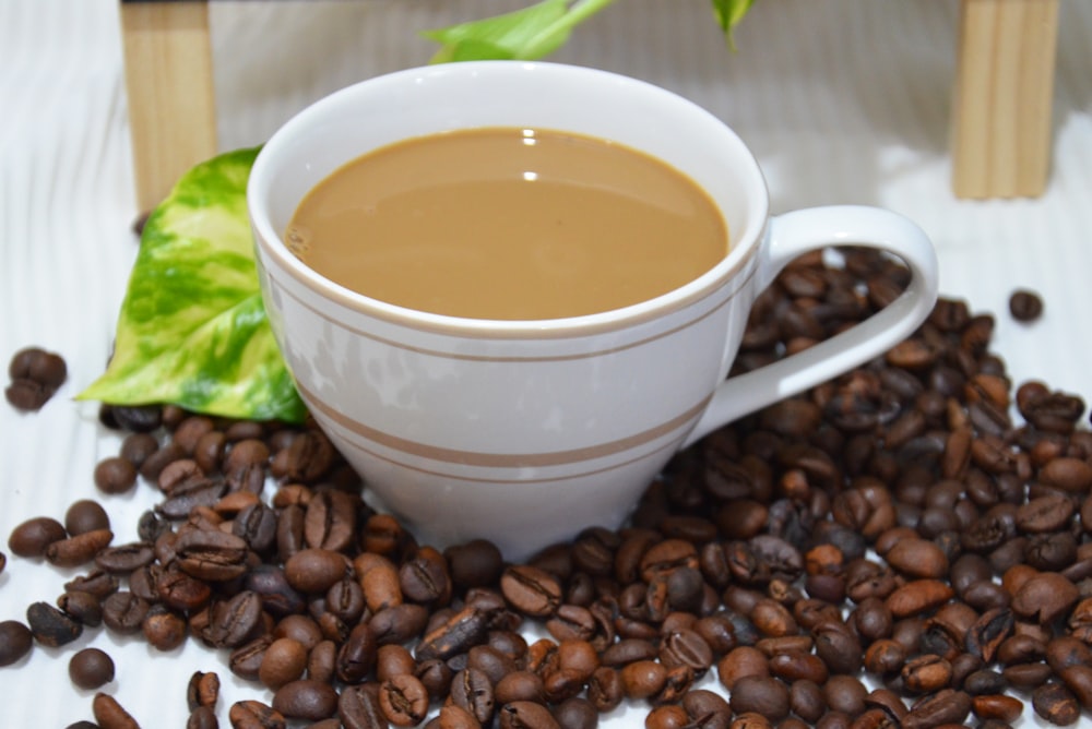 a cup of coffee sitting on top of a pile of coffee beans