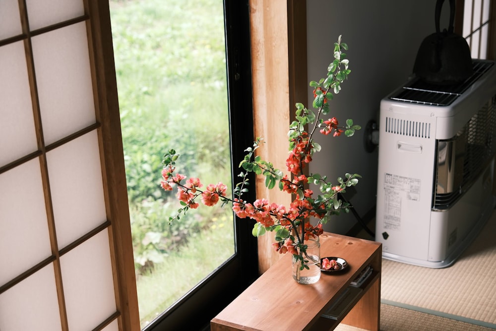 a vase with flowers on a table next to a window