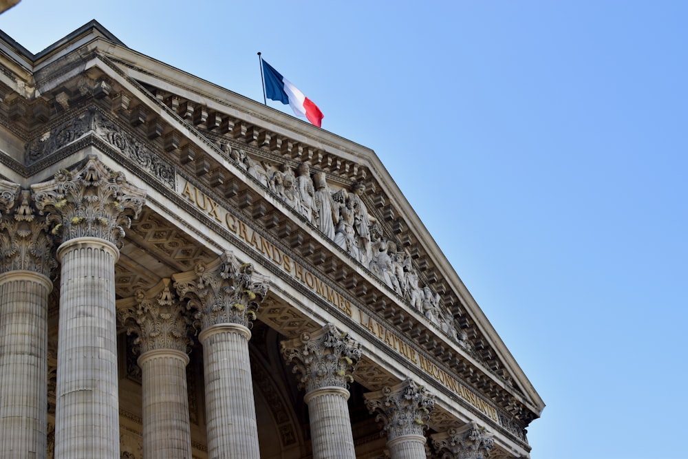 a tall building with columns and a flag on top of it