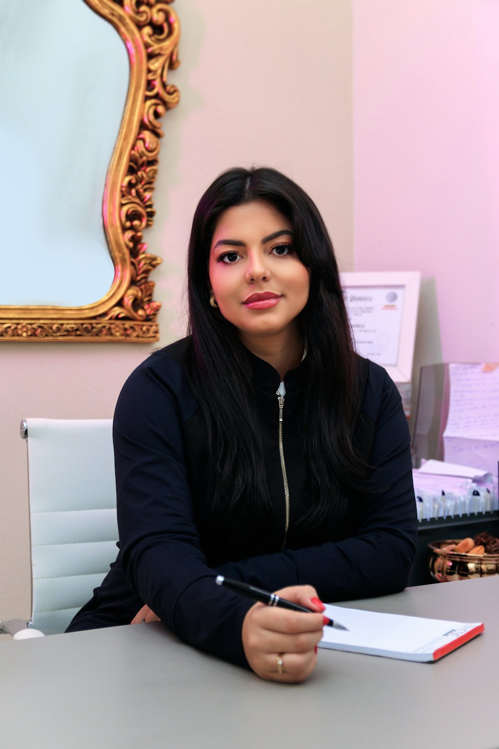 a woman sitting at a desk with a pen in her hand