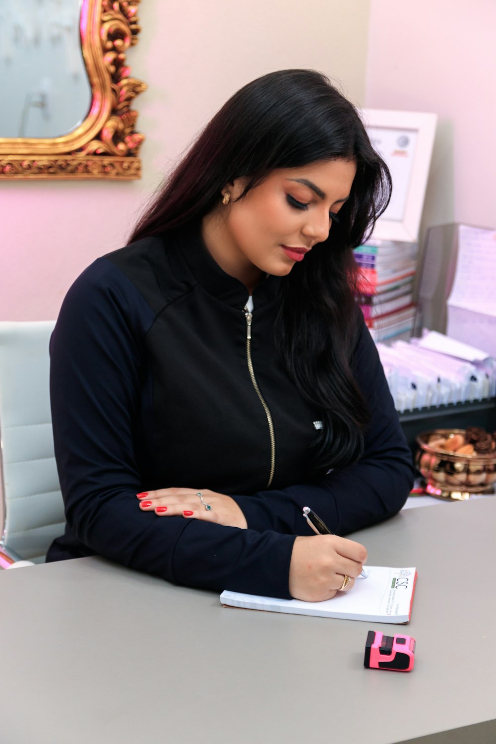 a woman sitting at a desk writing on a piece of paper