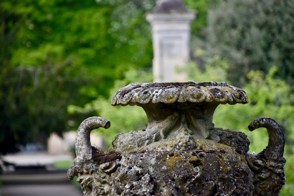 a stone urn with a statue in the background