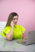 Close-up of a smiling young woman speaking on a headset in a bright office.